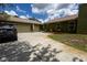 Long driveway leading to a two-car garage and a well-maintained lawn with lush greenery at 7550 Jomel Dr, Weeki Wachee, FL 34607