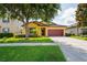 Charming yellow single-story home featuring a well-manicured lawn, mature tree, and a two-car garage at 758 Alpine Thistle Dr, Brooksville, FL 34604