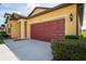 Exterior home view showcasing a two-car garage with a striking red garage door and manicured landscaping at 758 Alpine Thistle Dr, Brooksville, FL 34604