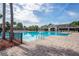 Serene community pool featuring a tranquil setting with palm trees and a clubhouse nearby at 758 Alpine Thistle Dr, Brooksville, FL 34604
