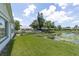 Backyard with green grass and lake view with lily pads and other homes on the lake at 7701 Anaheim Ave, New Port Richey, FL 34655