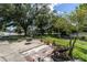 Backyard patio area, surrounded by green grass and mature trees, creates a cozy outdoor space at 7701 Anaheim Ave, New Port Richey, FL 34655