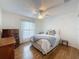 Sunlit bedroom features wood-look floors, neutral paint and a ceiling fan at 8130 Bugle Ct # 3, Port Richey, FL 34668