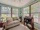 Bright and sunny Florida room with three large windows, light wood floors, and comfortable furnishings at 8130 Bugle Ct # 3, Port Richey, FL 34668