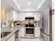 Bright kitchen featuring stainless steel appliances, granite countertops, and white cabinetry for storage at 8130 Bugle Ct # 3, Port Richey, FL 34668