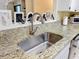 Close-up of a kitchen sink with stainless steel faucet, granite countertops, and white cabinetry at 8130 Bugle Ct # 3, Port Richey, FL 34668