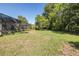 Expansive backyard with lush greenery and mature trees, partially enclosed by a screened enclosure, providing privacy and outdoor enjoyment at 9195 Bay Dr, Spring Hill, FL 34608