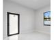 Minimalist bedroom featuring light walls, marble floors, and a black-framed exterior door at 9201 Nightingale Rd, Weeki Wachee, FL 34613