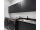 Modern laundry room with stainless steel sink and lots of black cabinets at 9201 Nightingale Rd, Weeki Wachee, FL 34613