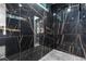 Luxurious shower with sleek black tile and gold veining throughout and hexagon patterned floor at 9201 Nightingale Rd, Weeki Wachee, FL 34613