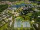 Breathtaking aerial view of a community with tennis courts, pool, clubhouse, lake, and lush greenery at 1009 Almondwood Dr, Trinity, FL 34655