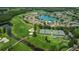 Aerial view showcasing a community with a golf course, tennis courts, lake, and well-manicured landscaping at 1009 Almondwood Dr, Trinity, FL 34655