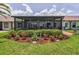 Charming backyard oasis featuring a screened patio and colorful flowerbeds at 1009 Almondwood Dr, Trinity, FL 34655