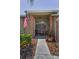 Inviting front porch with a red double door, American flag, and lovely landscaping around the walkway at 1009 Almondwood Dr, Trinity, FL 34655