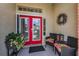 Inviting front porch with a red double door, decorative wreath, and outdoor seating with colorful cushions at 1009 Almondwood Dr, Trinity, FL 34655