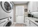 Efficient laundry room with stacked washer/dryer, granite counters, and ample cabinet space at 1009 Almondwood Dr, Trinity, FL 34655