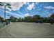 Well-maintained tennis court under a partly cloudy sky with great lighting for evening games at 1009 Almondwood Dr, Trinity, FL 34655