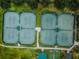 Aerial view of tennis courts featuring lights and pathways on a sunny day, perfect for active community living at 1009 Almondwood Dr, Trinity, FL 34655