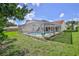 View of an inviting screened-in pool from the grassy yard, surrounded by lush landscaping at 10285 Rosetti Ct, Spring Hill, FL 34608