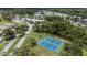 Aerial view of the community featuring tennis courts, mature trees, and a pond at 11621 Pear Tree Dr, New Port Richey, FL 34654