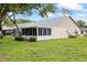 Exterior home view featuring a spacious backyard, screened lanai, and lush landscaping at 11621 Pear Tree Dr, New Port Richey, FL 34654