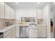 Bright kitchen featuring white cabinetry, stainless steel dishwasher, and a pass-through to the living area at 11621 Pear Tree Dr, New Port Richey, FL 34654