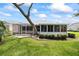 Enclosed sunroom with lots of windows overlooks the landscaped backyard with a mature tree and manicured shrubs at 11621 Pear Tree Dr, New Port Richey, FL 34654