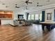Spacious living room with lots of seating, wood floors, ceiling fans, and access to the kitchen and pool table at 13600 Crest Lake Dr, Hudson, FL 34669
