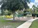 A community playground with swings, slide, picnic table and mature trees at 13600 Crest Lake Dr, Hudson, FL 34669
