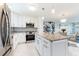 Bright kitchen with a granite countertop island, stainless steel appliances, and white cabinets, adjacent to the living area at 1365 Snell Isle Ne Blvd # 1B, St Petersburg, FL 33704