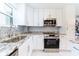Bright kitchen featuring granite counters, stainless steel appliances, and white cabinetry at 1365 Snell Isle Ne Blvd # 1B, St Petersburg, FL 33704