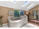 Bathroom featuring large bathtub with skylights, neutral tile, and a view to the garden at 1430 Rosetree Ct, Clearwater, FL 33764