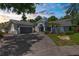 Beautiful home featuring lush landscaping, a curved driveway, a blue exterior, and a well-manicured lawn at 1430 Rosetree Ct, Clearwater, FL 33764