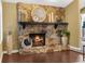 Living room fireplace with stone surround and dark wood mantle, decorated with a circular mirror and other home decor at 1430 Rosetree Ct, Clearwater, FL 33764