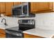 Modern stainless steel microwave and electric range against white tile backsplash at 14645 Spellman Ct, Spring Hill, FL 34610