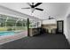 Covered outdoor kitchen with a bar, built-in grill, and ceiling fans by the pool at 14645 Spellman Ct, Spring Hill, FL 34610