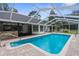 Screened-in swimming pool with brick pavers and adjacent covered outdoor kitchen and lanai at 14645 Spellman Ct, Spring Hill, FL 34610