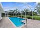 Swimming pool in a screened enclosure featuring brick pavers and metal handrails at 14645 Spellman Ct, Spring Hill, FL 34610