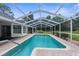 A screened-in pool with clear blue water surrounded by brick pavers provides a relaxing backyard oasis at 14645 Spellman Ct, Spring Hill, FL 34610