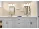 Bathroom with double sinks, white cabinets, and decorative mirrors at 15004 Middle Fairway Dr, Spring Hill, FL 34609