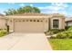 House exterior with a beige two car garage, green grass, and tasteful front yard landscaping at 15004 Middle Fairway Dr, Spring Hill, FL 34609