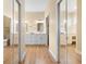 Hallway with mirrored closets, wood floors, and views into adjoining bathrooms at 15004 Middle Fairway Dr, Spring Hill, FL 34609