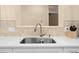 Close-up of a stainless steel kitchen sink with stone backsplash and light countertops at 15004 Middle Fairway Dr, Spring Hill, FL 34609