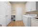 Functional laundry room features a washer, dryer, storage cabinets, and wood floor at 15004 Middle Fairway Dr, Spring Hill, FL 34609