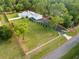 Aerial view showcases the property, including a spacious yard, white fence, and long driveway at 15430 Oakcrest Cir, Brooksville, FL 34604