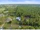 Expansive aerial view of property with lush greenery, white fencing, and multiple structures at 15430 Oakcrest Cir, Brooksville, FL 34604