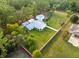 Aerial view of the house with expansive green lawn and surrounding trees with white picket fencing at 15430 Oakcrest Cir, Brooksville, FL 34604