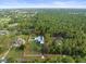 Expansive aerial view of property with lush greenery, white fencing, and multiple structures at 15430 Oakcrest Cir, Brooksville, FL 34604