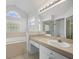 Bright bathroom with large mirror, dual sinks, soaking tub and glass-enclosed shower at 15430 Oakcrest Cir, Brooksville, FL 34604