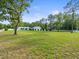 Lovely shot of the spacious lawn, white perimeter fence and garages in the distance at 15430 Oakcrest Cir, Brooksville, FL 34604